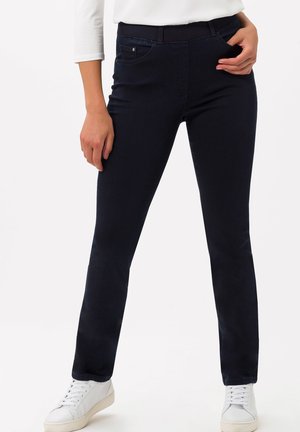 Donkerblauwe skinny jeans van rekbare stof, met een voorzak, riemlussen en een gladde textuur, gecombineerd met witte sneakers.