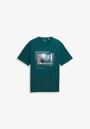 Tyrkysové tričko s krátkym rukávom s fotografickou potlačou okna a priemyselnej konštrukcie, vrátane textu "Everyday/All week" a "Creative Atelier."