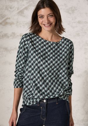 T-shirt à manches longues avec un motif sombre présentant des formes géométriques dans des teintes de vert et de bleu ; coupe ample, encolure ronde et texture de tissu douce.