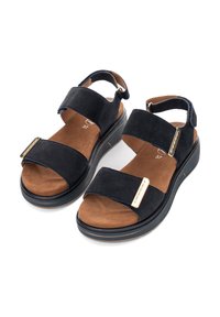 Schwarze Wildledersandalen mit zwei breiten Riemen und einem braunen gepolsterten Fußbett. Mit einem goldenen Akzentdetail an den Riemen und einer dicken Sohle.