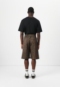 Black t-shirt, leopard print shorts with elastic waistband, knee-length, featuring white side stripes, textured fabric. White socks with black stripes.