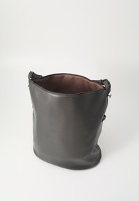 Sac seau en cuir noir avec une texture lisse, fermeture éclair et un intérieur brun doux. Dispose de sangles ajustables sur les côtés.