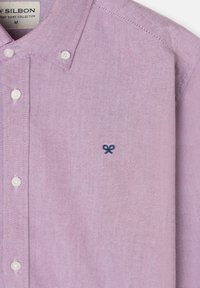 Camisa de botones de color púrpura claro hecha de una tela texturizada, con un pequeño logo bordado en navy y botones blancos en el frente.