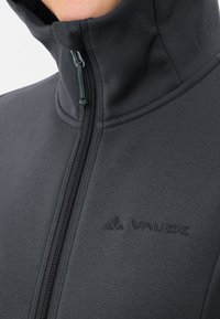 Giacca in pile nera con colletto alto, zip frontale e branding sottile. Texture morbida e finitura liscia, con dettagli di cucitura rinforzata.