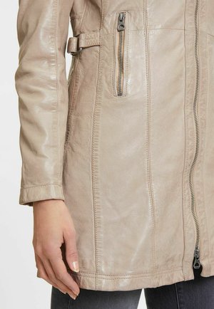 Beige leren jas met een gladde textuur, voorzien van een zijritszak, decoratieve stiknaden en een tailledetail met riem.