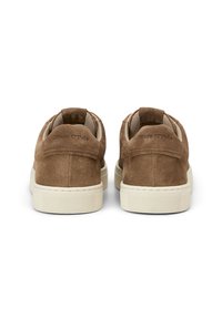 Braune Wildleder-Sneaker mit einer beigen Gummisohle. Verfügt über einen gepolsterten Kragen und eine Zunge, mit dezentem Branding auf der Rückseite.