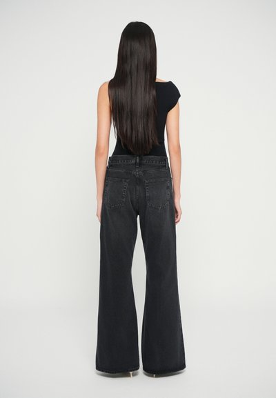 Sorte denim bukser med vid ben og høj talje, store baglommer og en let trykt tekstur. Stylet med en tætsiddende sort top.