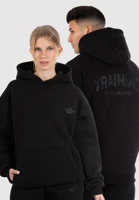 Zwarte hoodie van katoenmix, met een voorzak, trekkoordcapuchon en geprinte "TRAINING" logo op de achterkant en de borst.