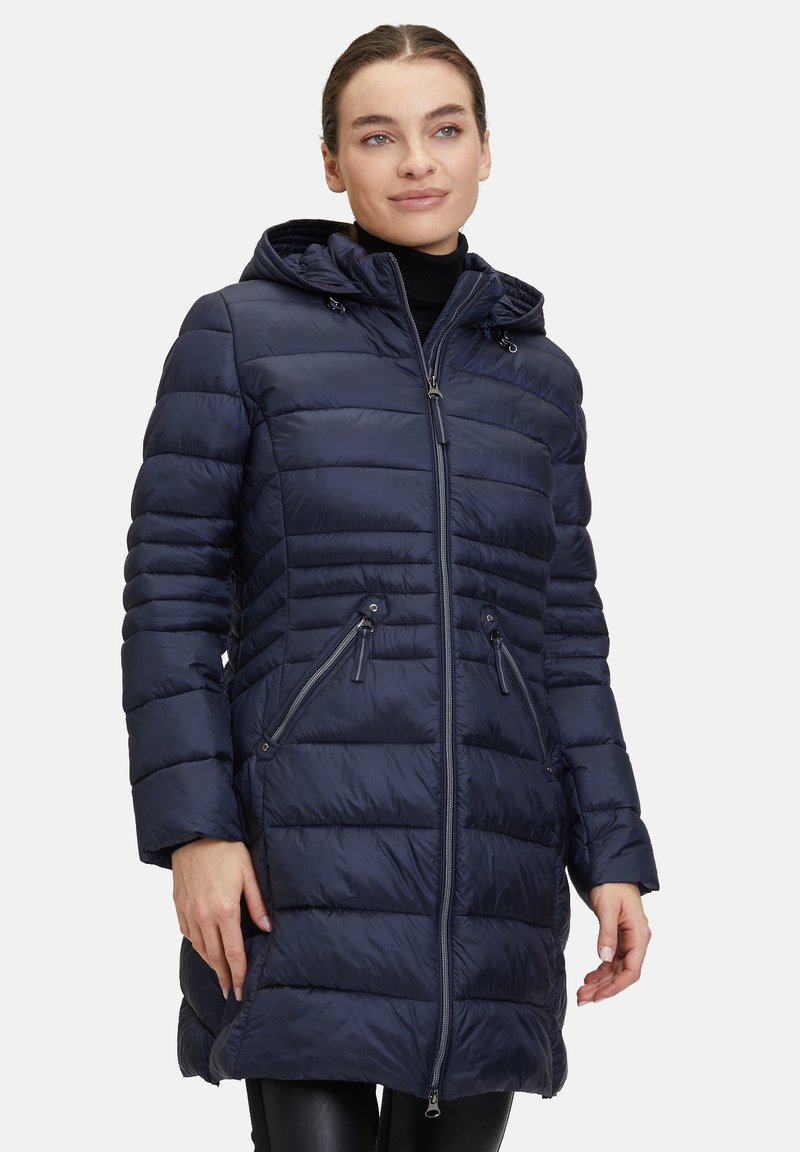 Doudoune bleue marine avec capuche, présentant des coutures horizontales, une fermeture éclair sur le devant et des poches, et une longueur mi-cuisse pour plus de chaleur.