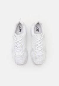 Egy pár fehér New Balance futócipő, hálós és szintetikus felsőrésszel, felülről nézve, fehér háttérrel.