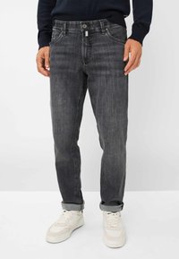 Jeans in denim grigio scuro con taglio dritto, cinque tasche e chiusura con bottone, caratterizzati da un leggero sbiadimento e orli arrotolati. Abbinati a sneakers bianche.