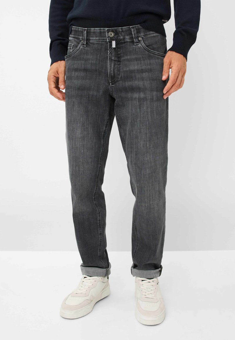 Jeans in denim grigio scuro con taglio dritto, cinque tasche e chiusura con bottone, caratterizzati da un leggero sbiadimento e orli arrotolati. Abbinati a sneakers bianche.