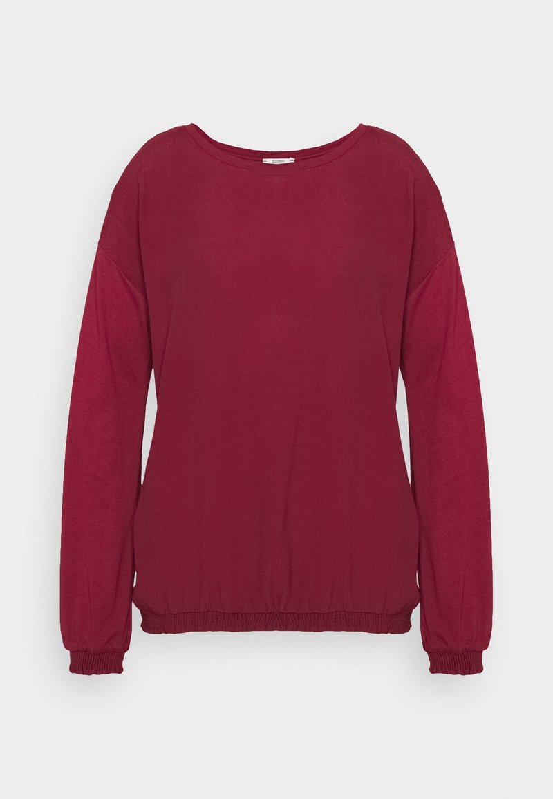 Długi rękaw bordowy sweter z elastycznymi mankietami i dołem, a także szerokim okrągłym dekoltem, na jednolitym jasnym tle.