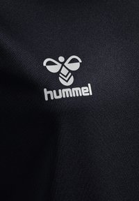 Svart sporttyg med en slät yta, med en vit logotyp av en bi och "hummel" i en modern sans-serif typsnitt.