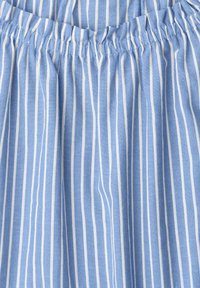 Tissu bleu à rayures blanches verticales avec une ceinture élastique froncée, montrant la texture et les détails des coutures.