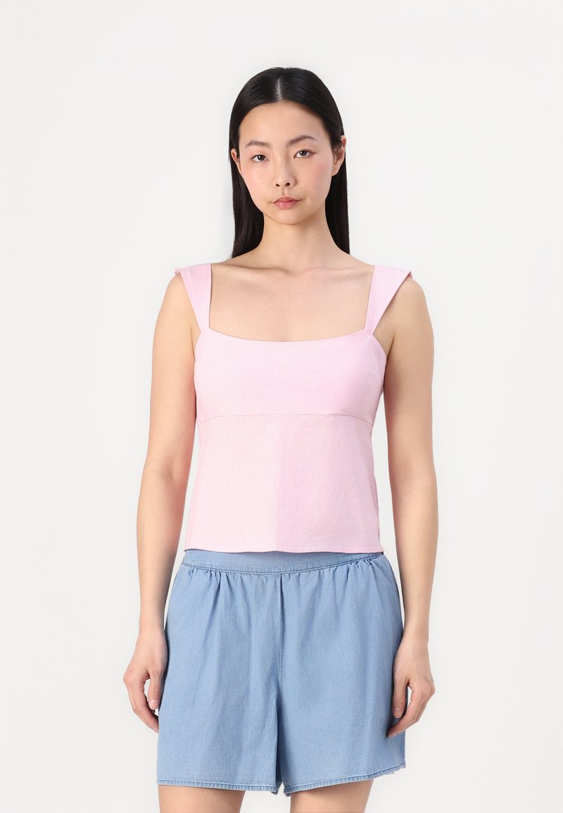 Top corto rosa con escote cuadrado y tirantes anchos, combinado con pantalones cortos sueltos de color azul claro, fabricados en una tela suave y con un ajuste relajado.
