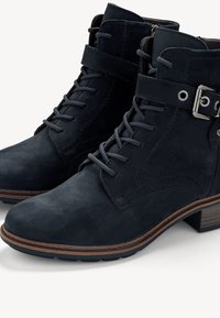 Bottines en suédine bleu foncé à lacets, avec une boucle sur le côté et un accent en bois sur le talon pour un détail supplémentaire.