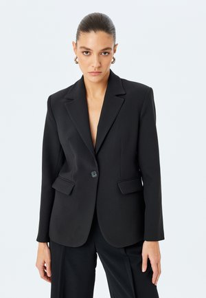 Blazer nero realizzato in tessuto liscio, con chiusura a bottone singolo, due tasche frontali e design con revers a punta.