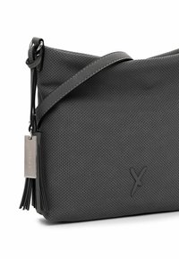 Gray perforated leather bag with a flat design, adjustable strap, tassel accent, and a small metal tag, featuring a subtle embossed logo.
