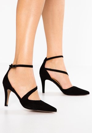 Zwarte suède pumps met een spits toelopende neus, voorzien van dubbele enkelbandjes en een slanke naaldhak. Glad leer met een minimalistisch design.