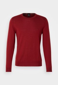 Pull rouge en tricot avec un col rond, des manches longues, des poignets et un ourlet côtelés, présentant un détail de logo subtil sur la poitrine.