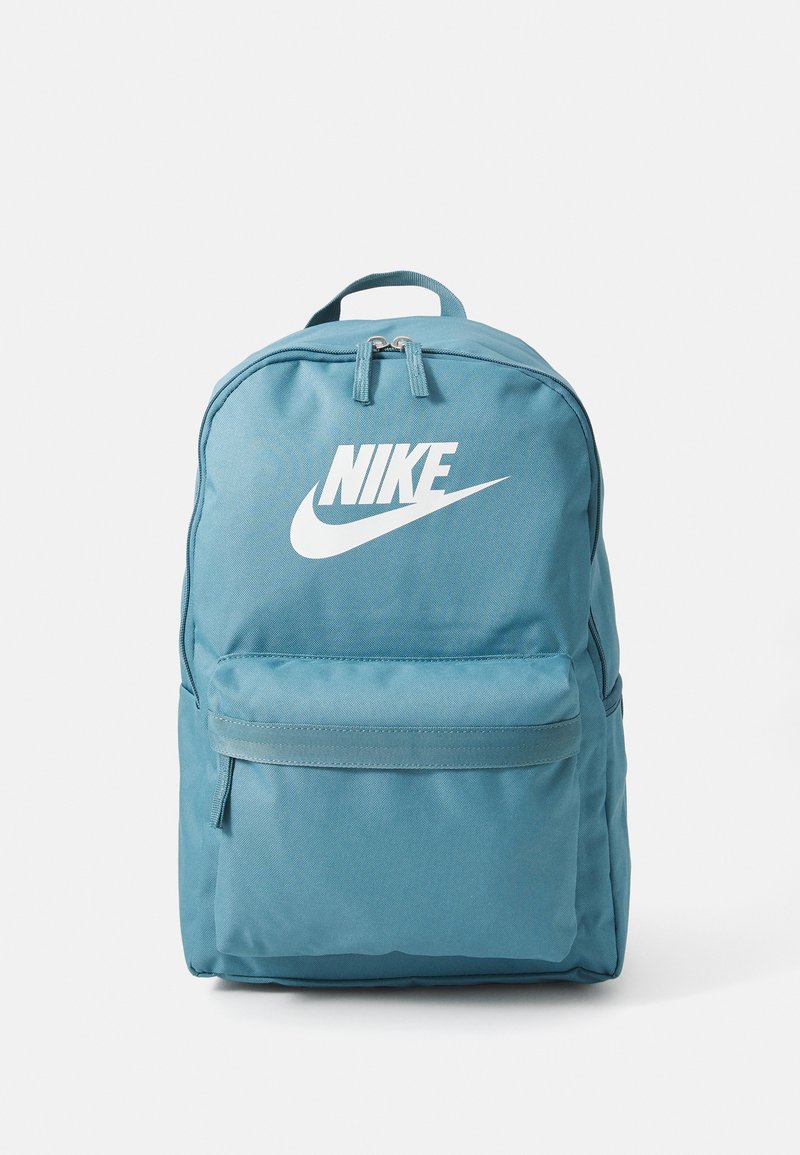 Tirkizni ruksak napravljen od izdržljive tkanine, s velikim bijelim Nike logotipom, zatvorom na vrhu sa zatvaračem i prednjim džepom sa zatvaračem.