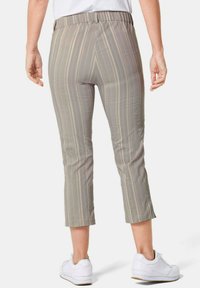 Lichtgrijze cropped broek met verticale strepen in beige. Elastische tailleband, gladde textuur en een slim fit, gecombineerd met witte sneakers.