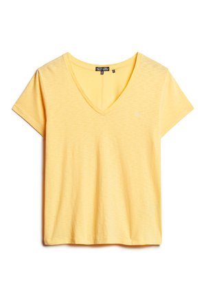 T-shirt jaune à col en V fabriqué en tissu doux et texturé. Doté de manches courtes et d'un petit logo sur la poitrine. Ajustement décontracté et relaxed.