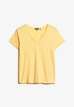 T-shirt jaune à col en V fabriqué en tissu doux et texturé. Doté de manches courtes et d'un petit logo sur la poitrine. Ajustement décontracté et relaxed.