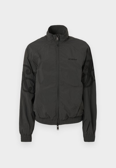 Μαύρο ελαφρύ μπουφάν με όρθιο γιακά, μπροστινό φερμουάρ, ελαστικές μανσέτες και διακοσμητική κέντηση στα μανίκια. Λείος υφαντικός ιστός.