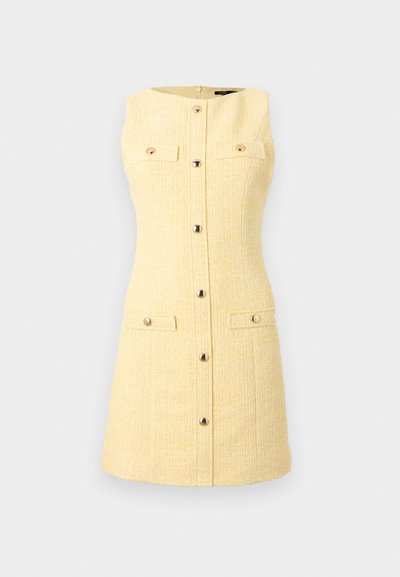 Μίνι φόρεμα από κίτρινο τουίντ χωρίς μανίκια, με κουμπιά στο μπροστινό μέρος και τέσσερις τσέπες με καπάκια, δύο στο στήθος και δύο κοντά στο τελείωμα.