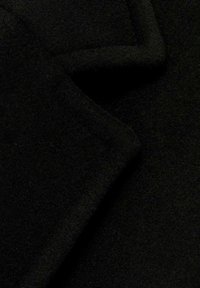 Material negru cu o suprafață moale și texturată, având margini pliate și cusături care creează un aspect stratificat.
