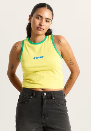 Geel kort tanktopje met contrasterende groene bies en blauw Vans-logo; zachte stof; aansluitend ontwerp; gedragen met donkere jeans met hoge taille.