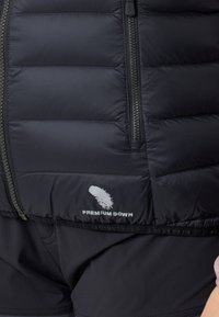 Svart uppblåsbar väst med horisontellt sydda paneler, en framsida med dragkedja och "PREMIUM DOWN"-logotyp i vitt nederst. Slät textur.