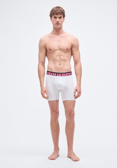 Calzoncillos tipo bóxer blancos con una cintura elástica negra y rosa que lleva el logo "DSQUARED2". Material de algodón suave, diseño ajustado, de longitud hasta mitad del muslo.