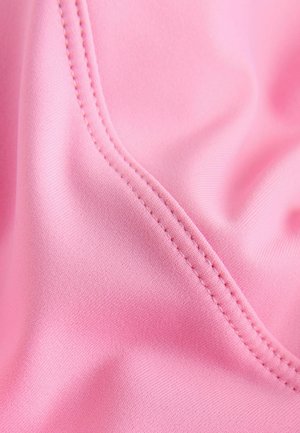 Pehme roosa kangas, millel on sile tekstuur, kõver serv ja nähtavad õmbluse detailid.