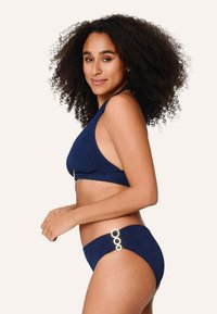 Námorně modrý bikinový set s texturovanou tkaninou. Vrchní díl má zavazování na krku a zlaté kování; spodní díl má tři kulaté akcenty po straně.