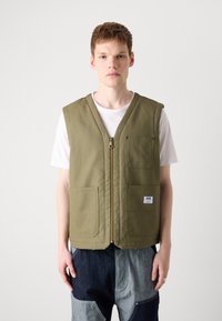 Olive green sleeveless vest with a front zipper, two front pockets, and a label patch. Crafted from durable fabric, offering a relaxed fit.