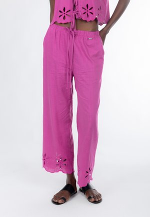 Pantalon rose, léger et respirant, avec une coupe décontractée, présentant des découpes florales à l'ourlet et une taille élastique avec un cordon de serrage.