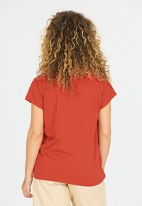 Kortærmet t-shirt i rustfarve lavet af blødt stof med rundet kant. Har en afslappet pasform og minimalistisk design.