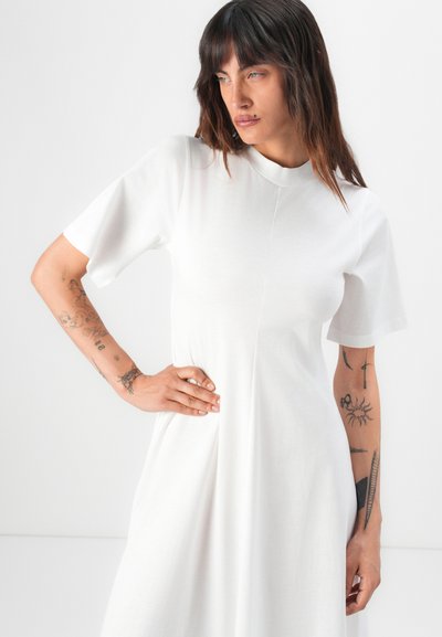 Weißes Kleid mit kurzen Ärmeln und hochgeschlossenem Ausschnitt, das eine glatte Textur und eine lässige Passform aufweist. Schlichtes Design mit dezenten Nahtdetails.