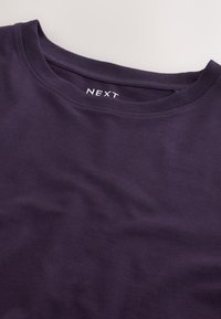 Mørklilla t-shirt med rund halsudskæring og korte ærmer. Fremstillet af blødt bomuldsstof med en diskret logomærkat indeni i kraven.