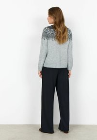 Pulover gri deschis cu un design de guler modelat în gri închis, asociat cu pantaloni largi negri. Textură moale, croială lejeră și mansete ribbate.