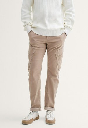 Beige Cargo-Hosen mit Seitentaschen, aus leichtem Stoff, mit einer entspannten Passform, umgeschlagenen Säumen und kombiniert mit weißen Sneakern.