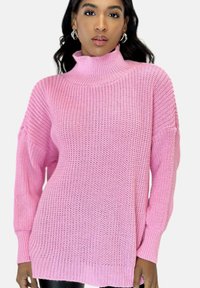 Maglione rosa lavorato a maglia con collo alto a lupetto, maniche lunghe e vestibilità ampia. Presenta polsini e orlo a coste con motivo a trama.