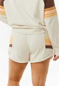 Shorts de color beige claro con acentos en bloques de color contrastantes en melocotón, marrón y naranja. Tela suave con un dobladillo redondeado y relajado.