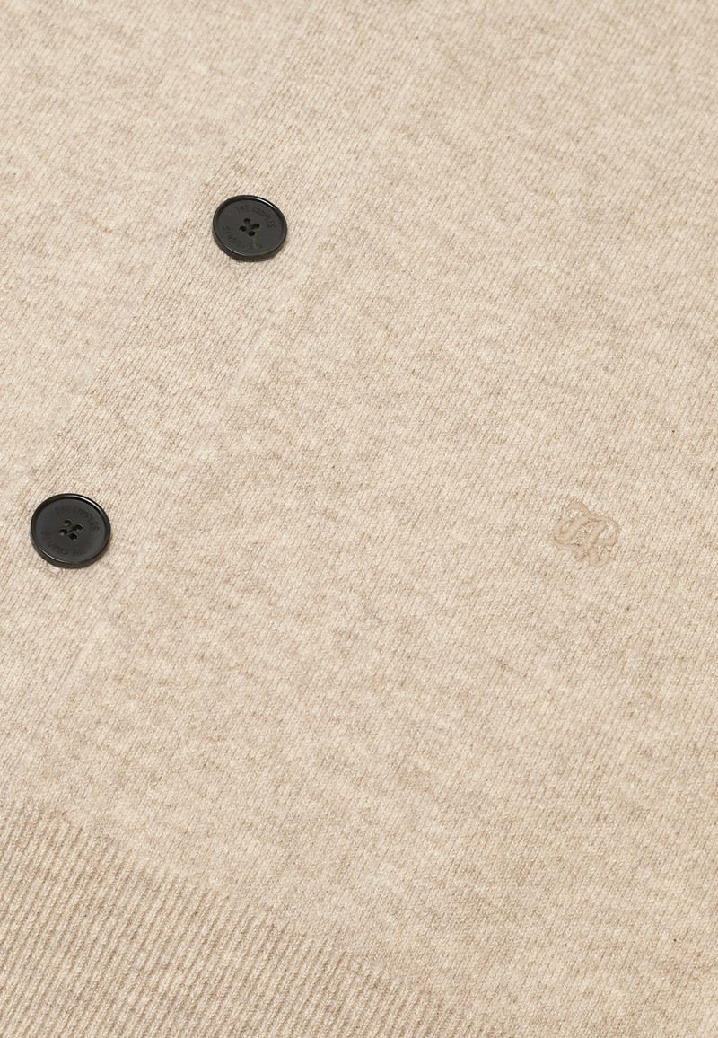 Beige gebreide cardigan met twee zwarte knopen. Heeft een ribbeltextuur en subtiele tonale merkbroderie op de stof.