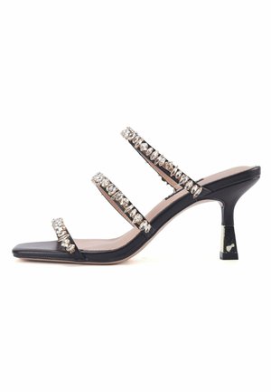 Black heeled sandal with three clear crystal-embellished straps, square toe, and a tapered heel with a metallic accent. Smooth leather finish.