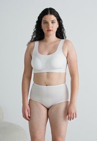 Hvit sømløs bralette og høybrystet undertøyssett, glatt tekstur, avrundede kopper og elastisk livlinje, vist mot en lys bakgrunn.