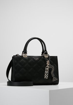 Zwarte doorgestikte handtas met dubbele handvaten, afneembare schouderriem en zilveren Guess-logo hanger met gestileerd sleutelgatontwerp.
